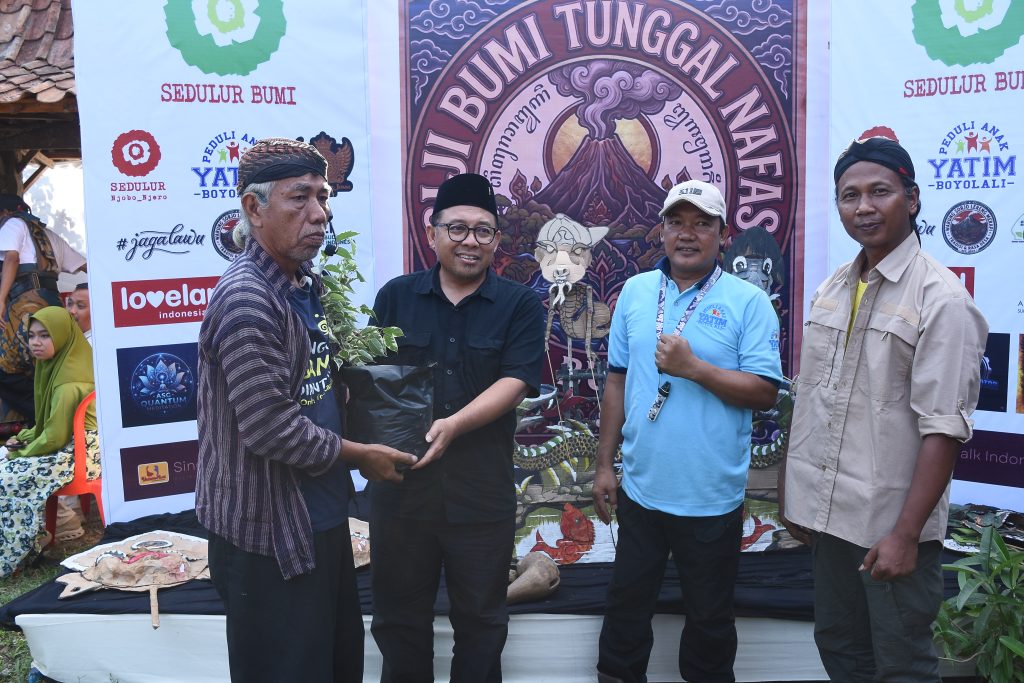 Ribut Budi Santoso sedang memberikan pohon beringin putih kepada dalang wayang keyong, Mbah Janthit untuk ditanam di Sendang Panguripan, didampingi oleh ketua PAYB, mas Jack, serta relawan Padepokan Klampis Ireng Sragen, Sugiono, Senin 20 April 2026
