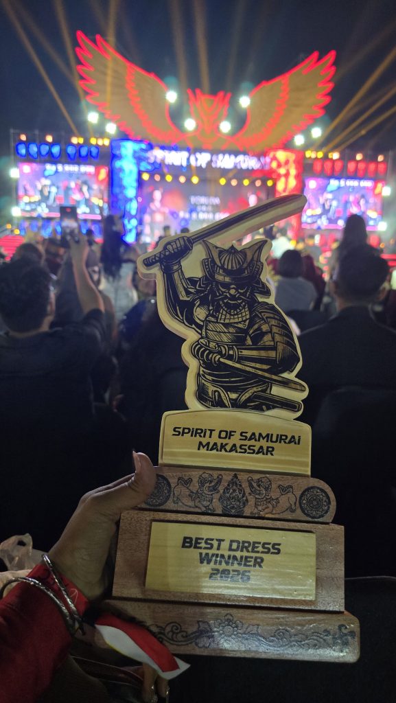 Piala Best Costum SOS Makasar yang dipegang Oleh Daimyo Erwin Arjayani dengan suasana panggung SOS VI Makasar Minggu malam, 26 April 2026
